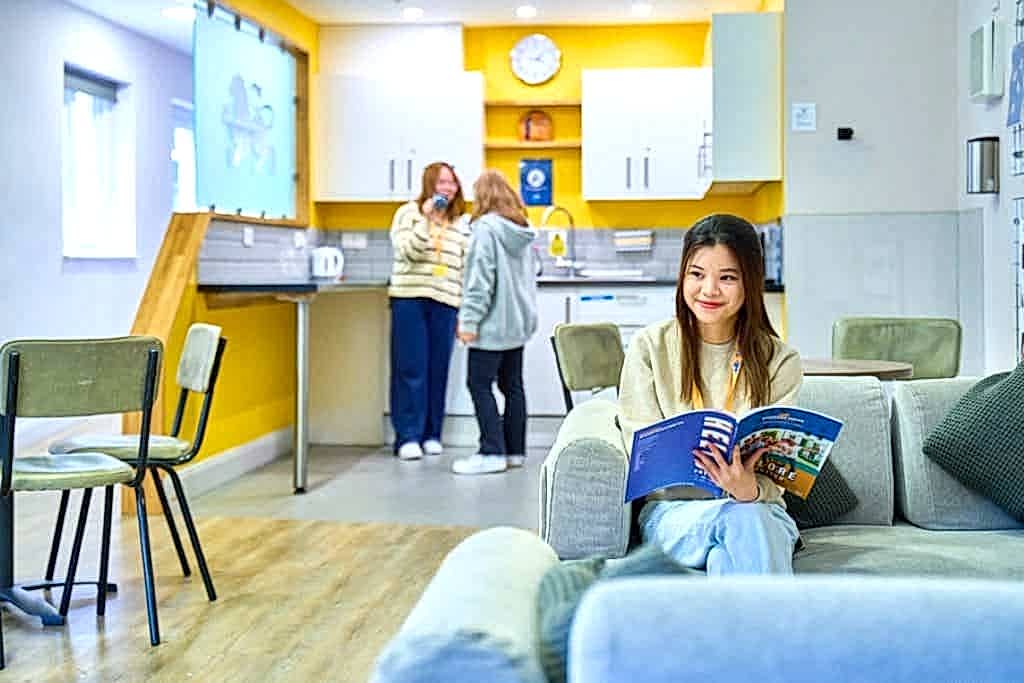Student reading a brochure on a sofa in the Stafford House Canterbury lounge
