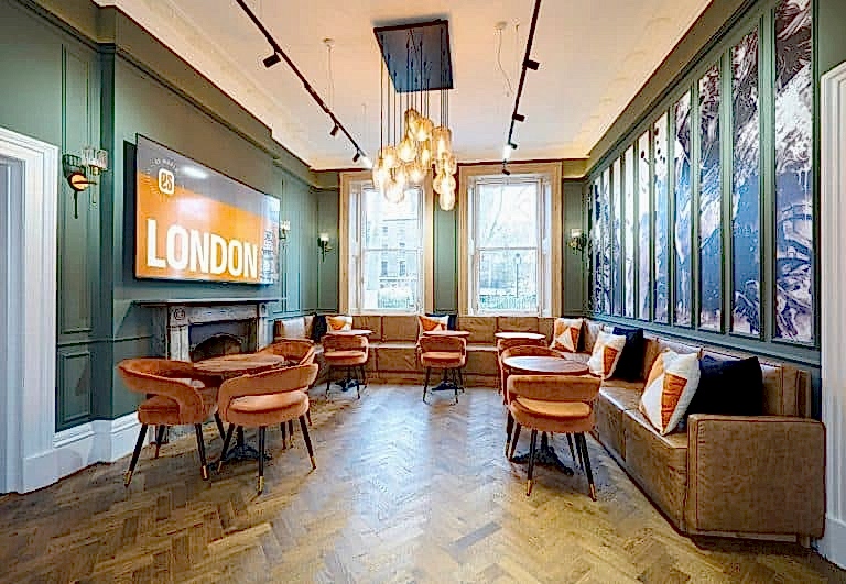 Student lounge with orange chairs, a sofa and a London sign at ES London