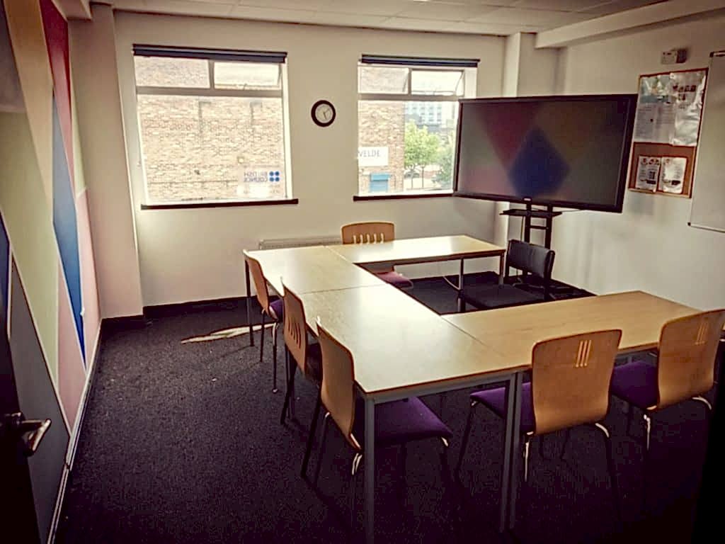 Empty classroom with tables in a U shape and a large screen at NIS Newcastle