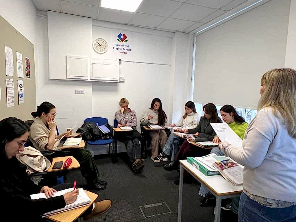 Teacher handing out worksheets to a class at Rose of York English School