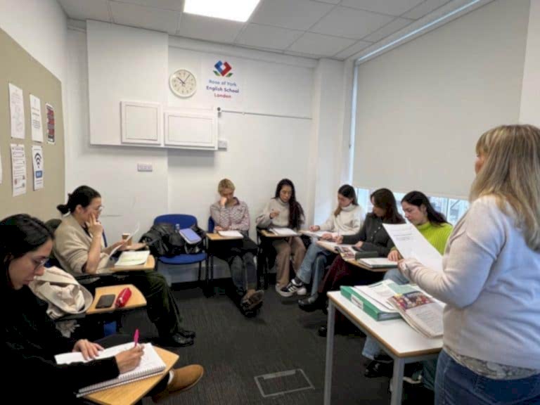 Teacher handing out worksheets to a class at Rose of York English School