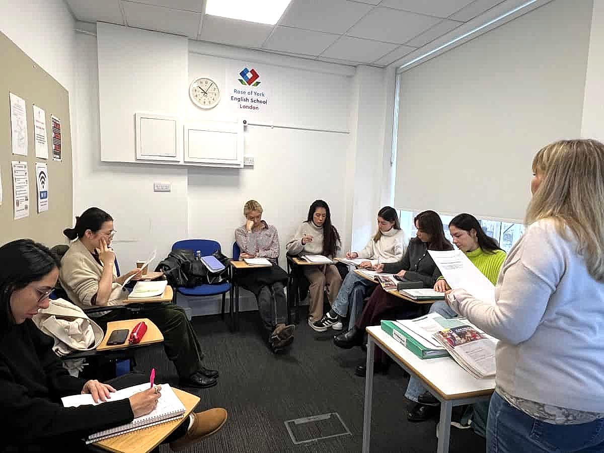 Teacher handing out worksheets to a class at Rose of York English School