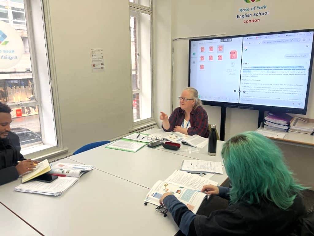 Teacher and students working from books beside a large screen at Rose of York