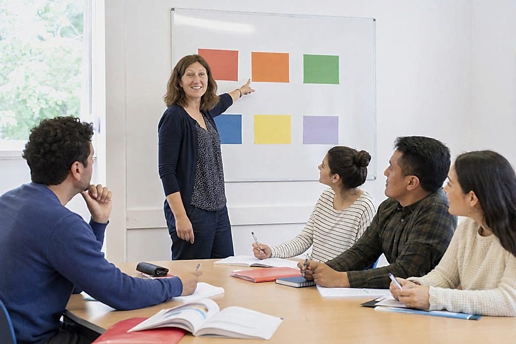 Teacher pointing at colour blocks on a whiteboard in an English class