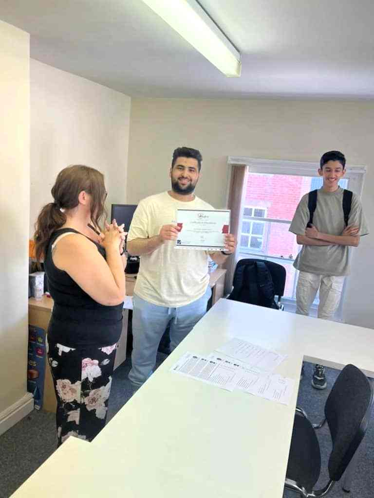 Student receiving a certificate from a teacher in a Sheffield Language Centre classroom