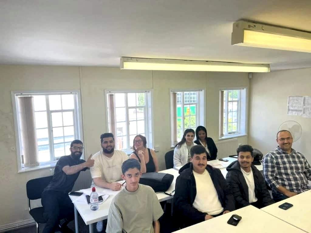 Class of students sitting at desks and smiling at Sheffield Language Centre