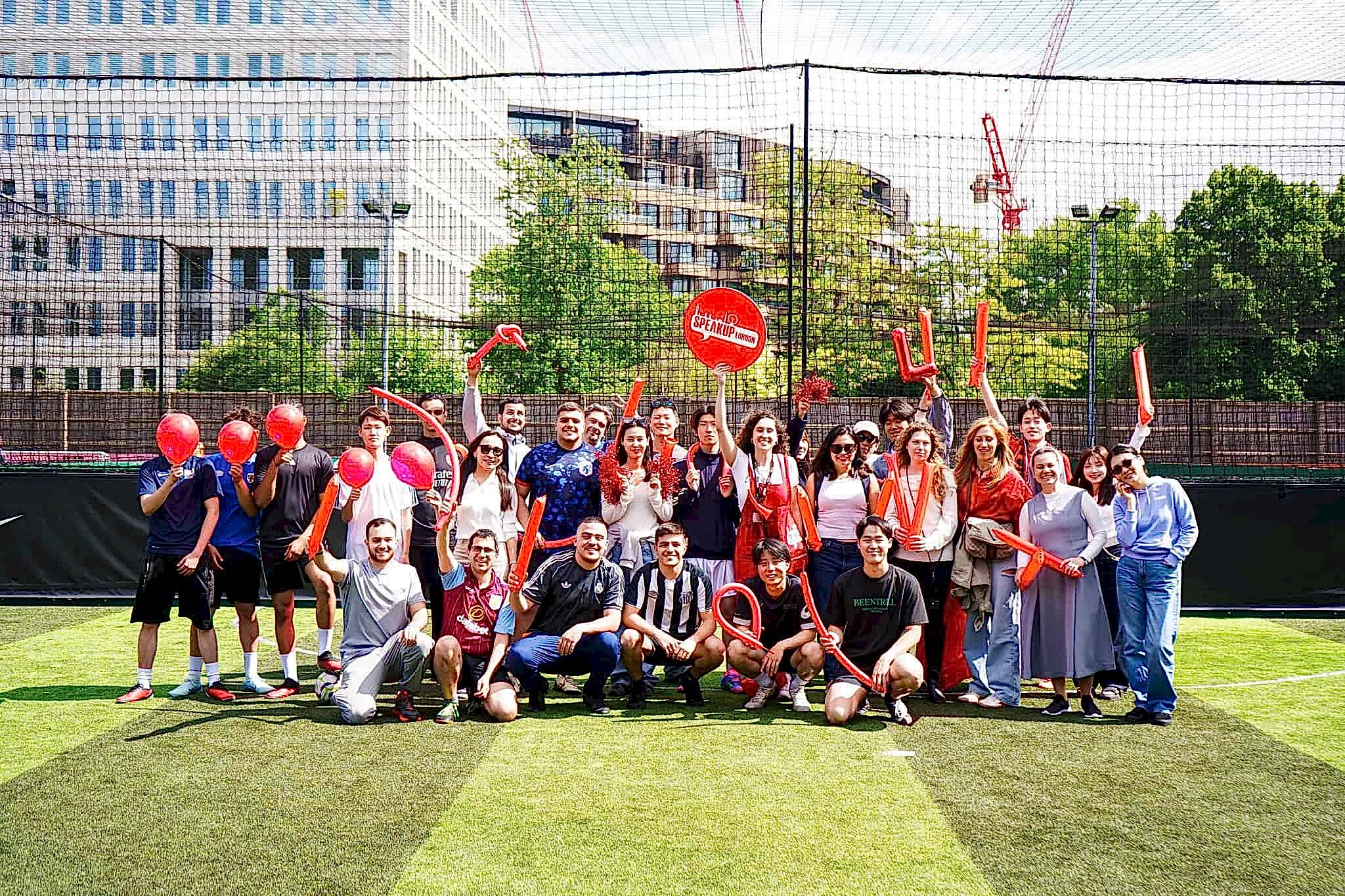 Speak Up London students posing with balloons on an outdoor football pitch