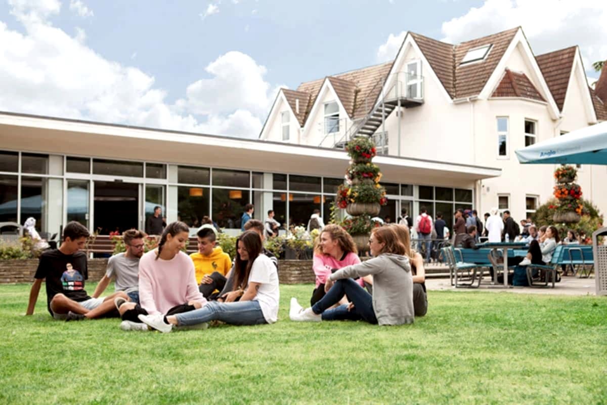 Des étudiants assis sur l'herbe dans les jardins d'Anglo-Continental à Bournemouth